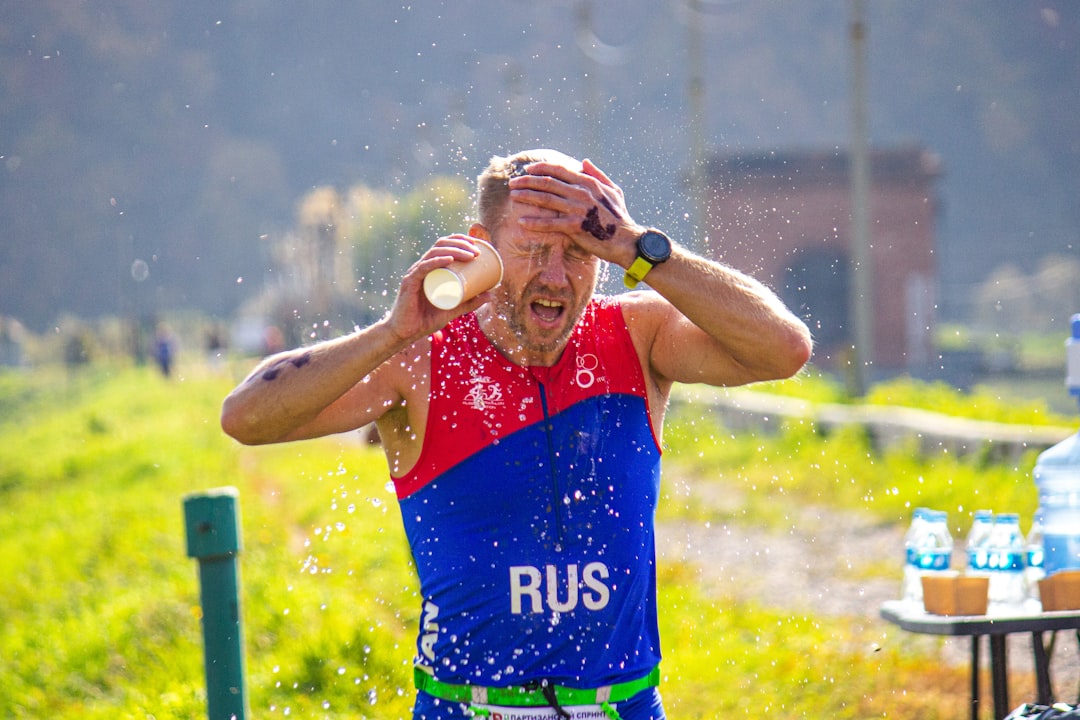 Photo by Dmitriy Ignatenko A man in a red, blue, and green shirt is drinking water from a